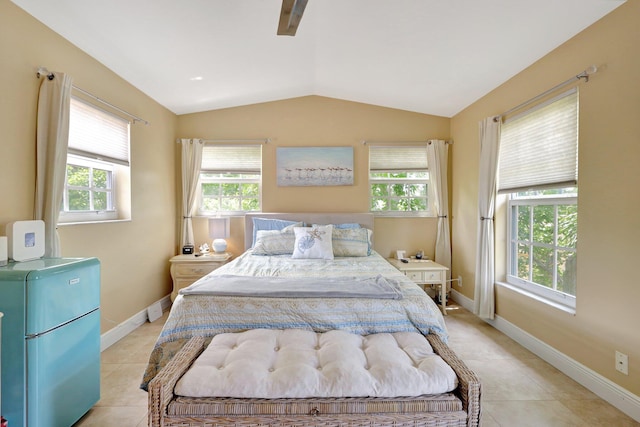 bedroom with multiple windows, vaulted ceiling, refrigerator, and light tile patterned flooring