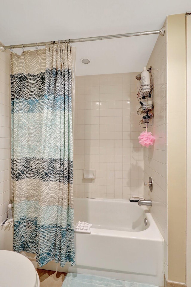 bathroom with shower / bathtub combination with curtain and toilet