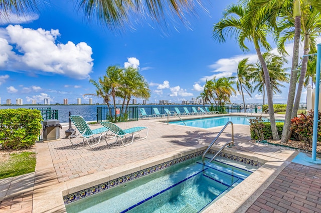 view of swimming pool featuring a water view, a hot tub, and a patio area