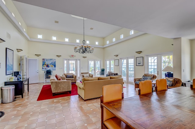 living room featuring french doors, a towering ceiling, and a notable chandelier