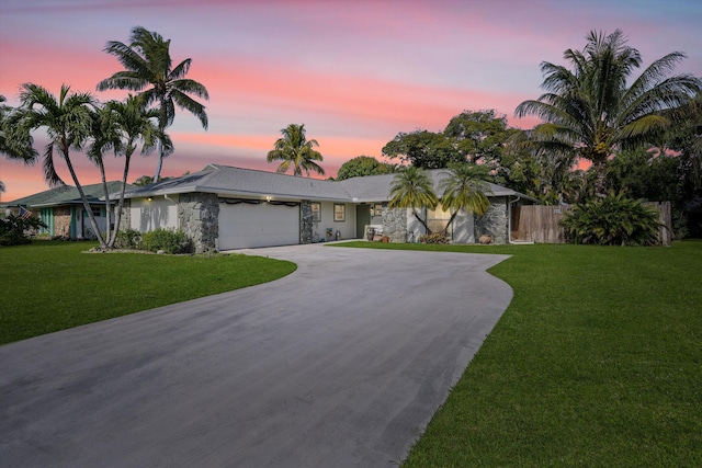 ranch-style home with a garage and a lawn