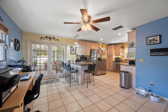 kitchen with french doors, a breakfast bar, light brown cabinets, appliances with stainless steel finishes, and pendant lighting