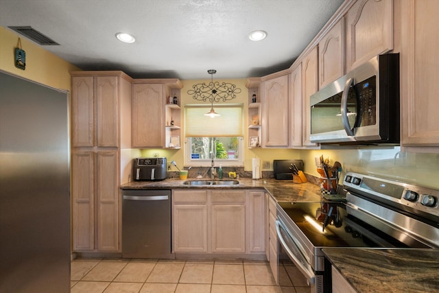 kitchen with light tile patterned floors, sink, hanging light fixtures, stainless steel appliances, and light brown cabinets