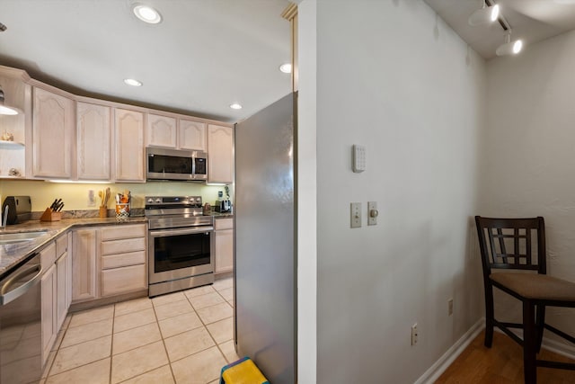 kitchen with appliances with stainless steel finishes, sink, light tile patterned floors, and light brown cabinetry