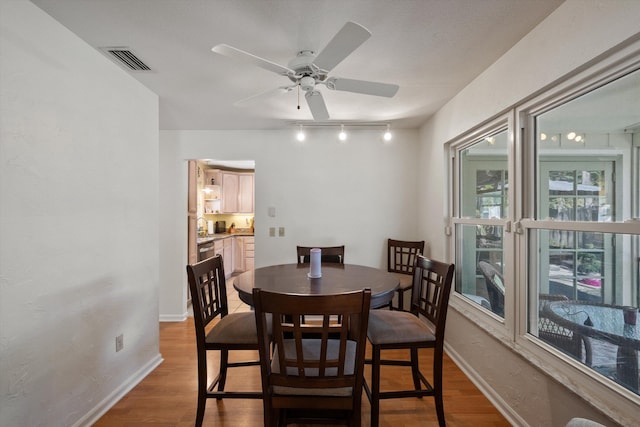 dining space with rail lighting, ceiling fan, and light hardwood / wood-style flooring