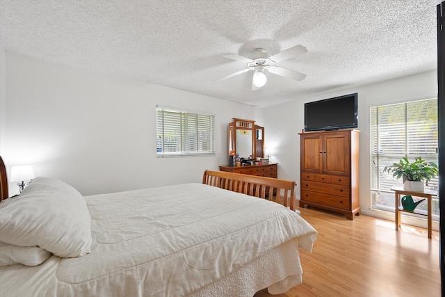 bedroom featuring ceiling fan, a textured ceiling, and light wood-type flooring