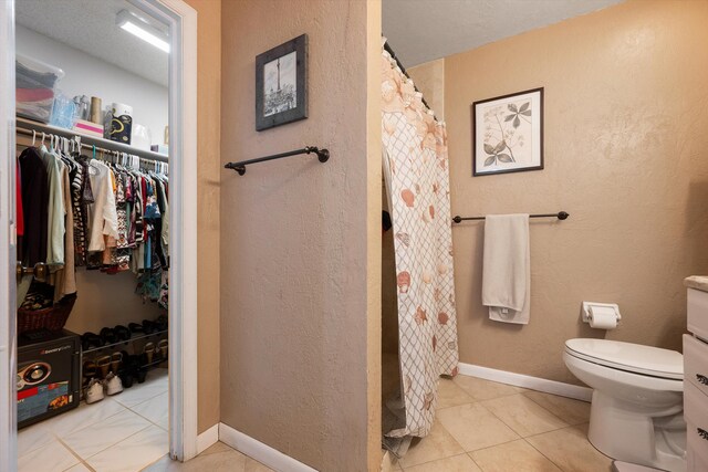 bathroom featuring toilet, curtained shower, and tile patterned flooring