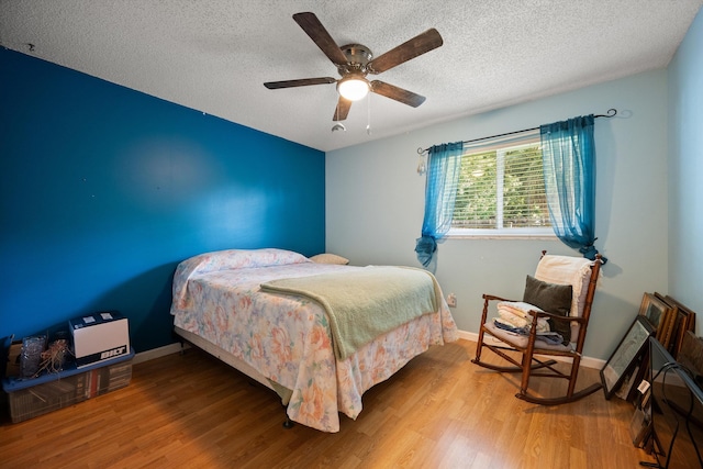 bedroom with ceiling fan, wood-type flooring, and a textured ceiling