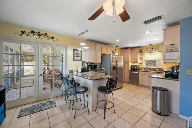 kitchen featuring a breakfast bar, light brown cabinets, appliances with stainless steel finishes, kitchen peninsula, and pendant lighting