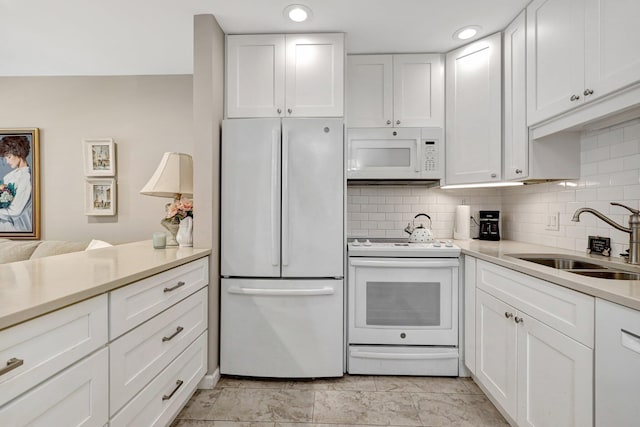 kitchen with sink, white cabinets, white appliances, and decorative backsplash