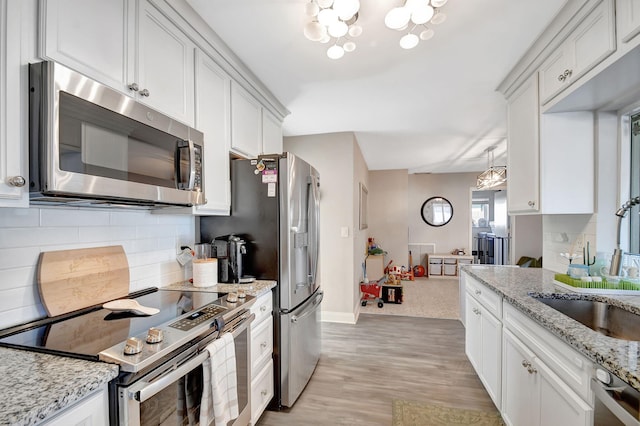 kitchen with stainless steel appliances, light stone countertops, and white cabinets