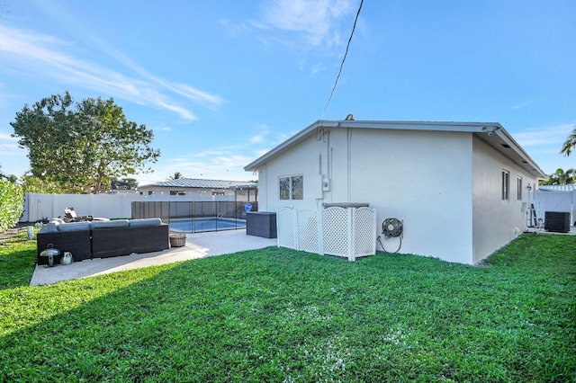 back of house with a fenced in pool, cooling unit, an outdoor living space, and a lawn