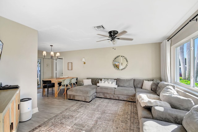 living room with ceiling fan with notable chandelier and wood-type flooring