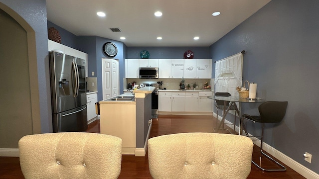 kitchen featuring dark wood-type flooring, sink, white cabinetry, a center island with sink, and stainless steel appliances