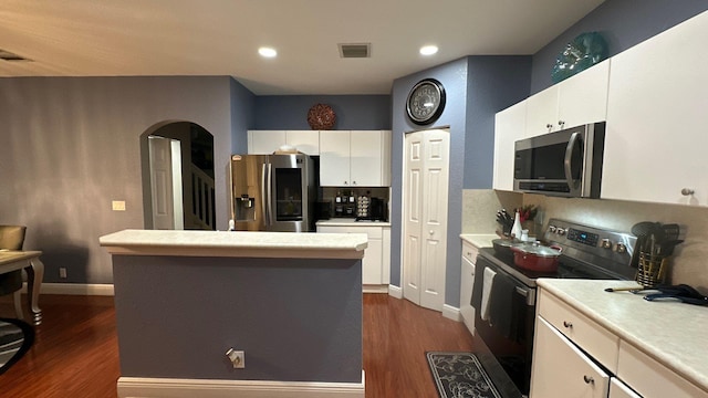 kitchen with white cabinetry, stainless steel appliances, dark hardwood / wood-style floors, and a kitchen island