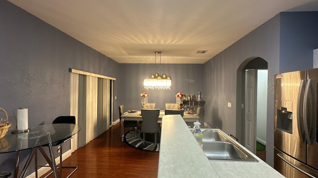 kitchen featuring dark wood-type flooring, sink, a chandelier, stainless steel fridge with ice dispenser, and hanging light fixtures