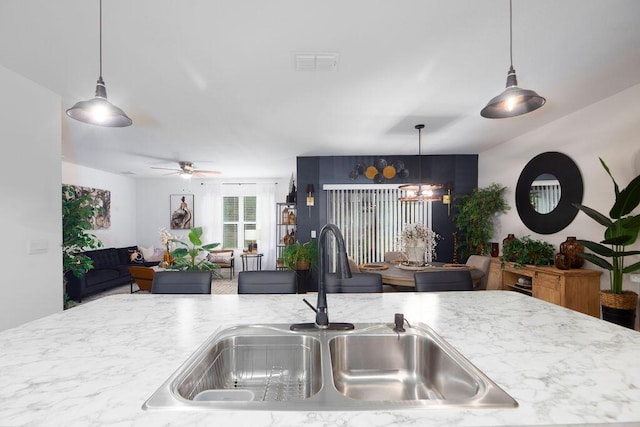 kitchen with ceiling fan with notable chandelier, sink, and pendant lighting