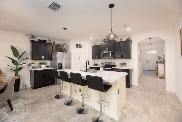 kitchen with sink, a center island with sink, hanging light fixtures, and appliances with stainless steel finishes