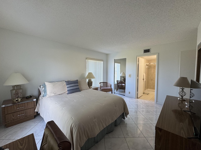 bedroom with connected bathroom, a textured ceiling, and light tile patterned floors