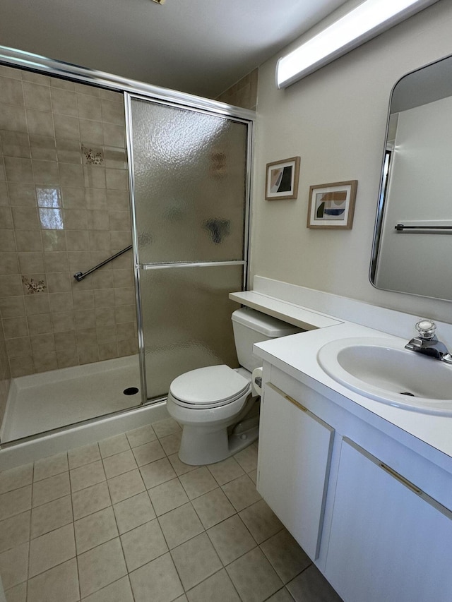 bathroom featuring tile patterned flooring, vanity, toilet, and an enclosed shower