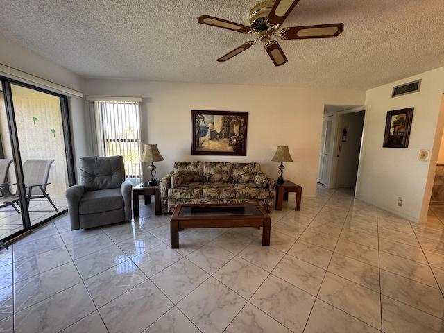 living room with ceiling fan and a textured ceiling