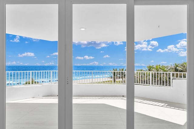 interior space featuring a balcony, a water view, and a view of the beach