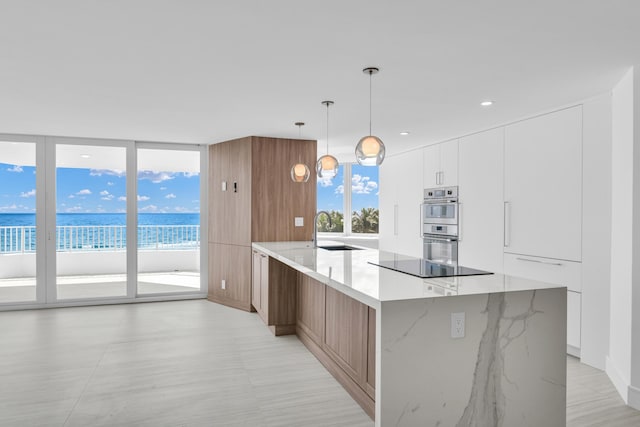 kitchen with a water view, black electric stovetop, hanging light fixtures, and white cabinets