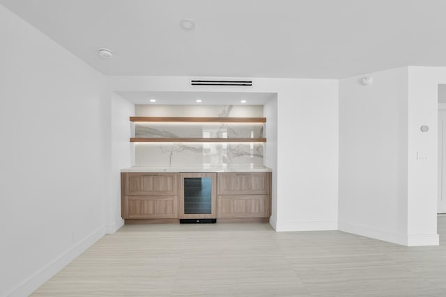 bar featuring wine cooler and light brown cabinets