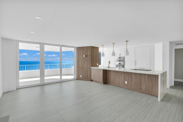 kitchen featuring double oven, decorative light fixtures, floor to ceiling windows, a water view, and black electric cooktop