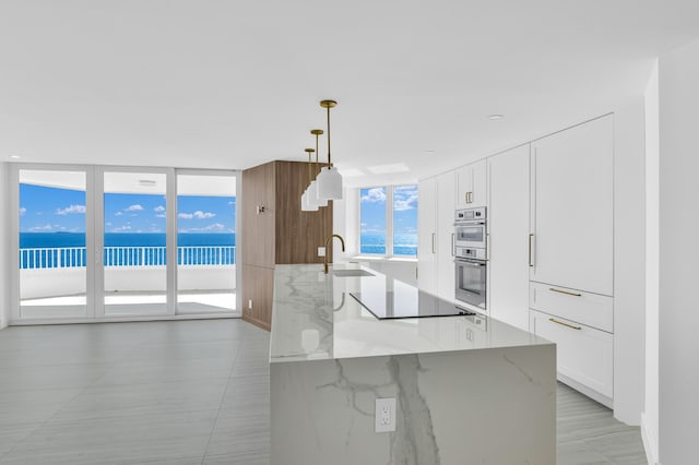 kitchen featuring pendant lighting, black electric stovetop, white cabinetry, and sink