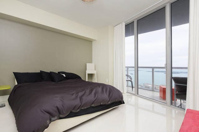 bedroom with access to exterior, expansive windows, and a water view