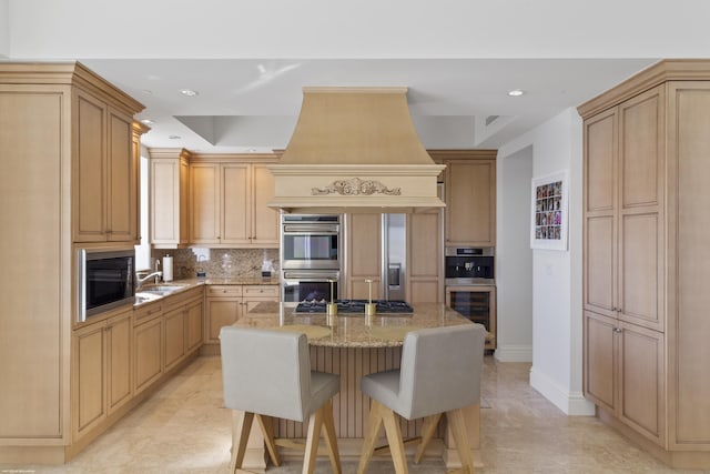 kitchen with light stone counters, black microwave, light brown cabinets, a kitchen island, and stainless steel double oven