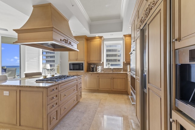 kitchen featuring black microwave, ornamental molding, custom range hood, stainless steel gas cooktop, and light brown cabinets