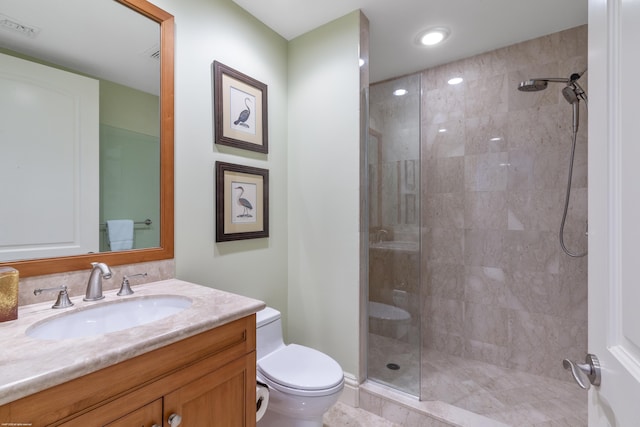 bathroom with vanity, toilet, and a tile shower