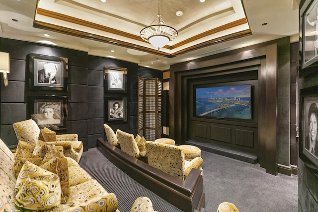 carpeted home theater with ornamental molding and a raised ceiling