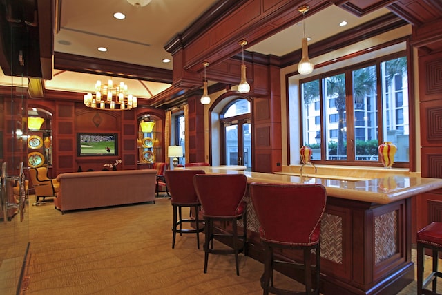 bar with ornamental molding, hanging light fixtures, and a notable chandelier