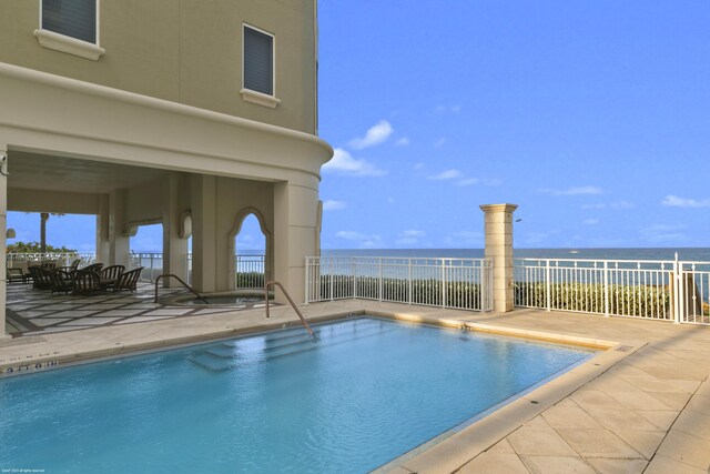 view of swimming pool featuring a patio and a water view