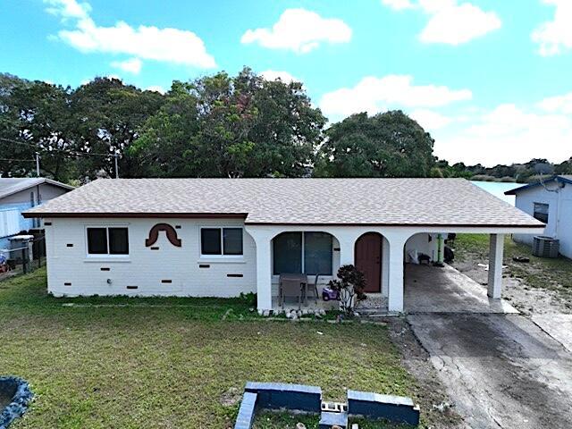 single story home with a front lawn, a carport, and covered porch