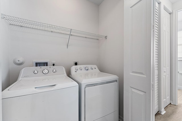 clothes washing area with washer and dryer and light wood-type flooring