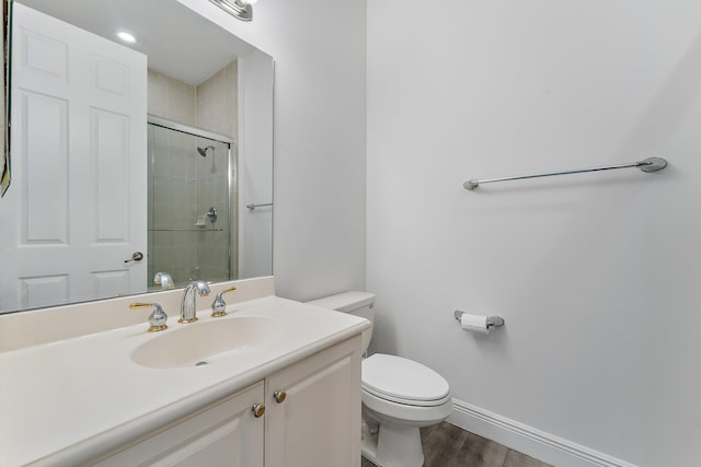 bathroom featuring hardwood / wood-style flooring, vanity, a shower with shower door, and toilet