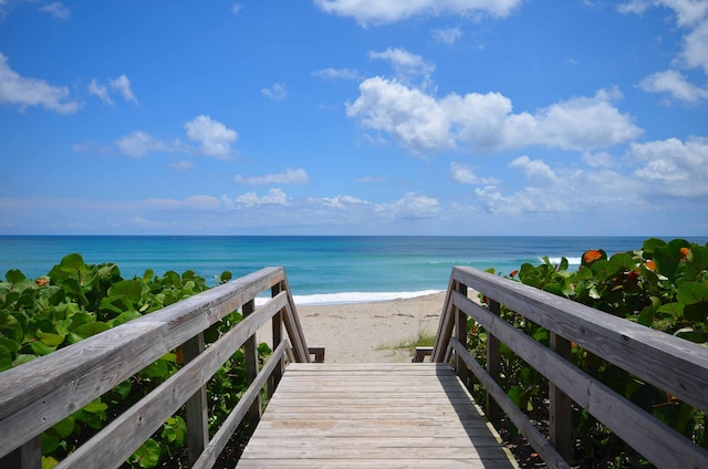 view of property's community with a water view and a beach view