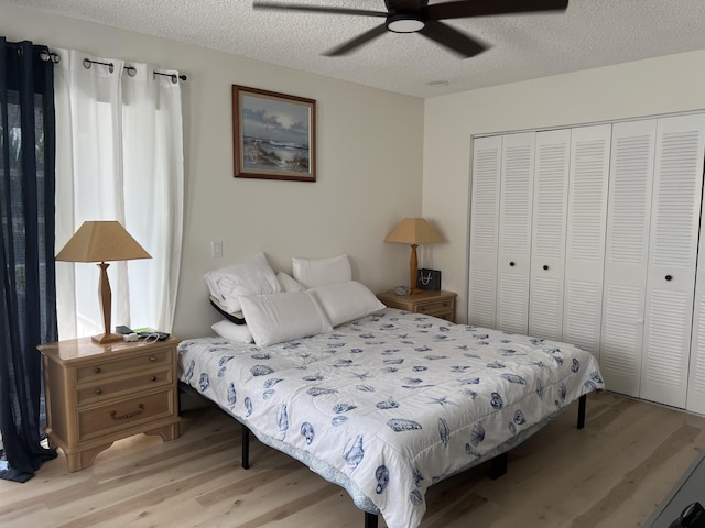 bedroom featuring ceiling fan, a closet, a textured ceiling, and light wood-type flooring