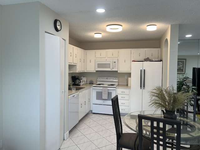 kitchen with light tile patterned flooring, sink, a textured ceiling, white appliances, and white cabinets