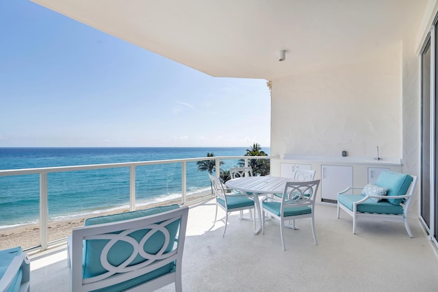 balcony with a water view and a view of the beach