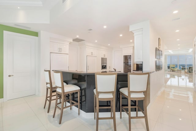 kitchen featuring white cabinetry, a breakfast bar, kitchen peninsula, and light tile patterned floors