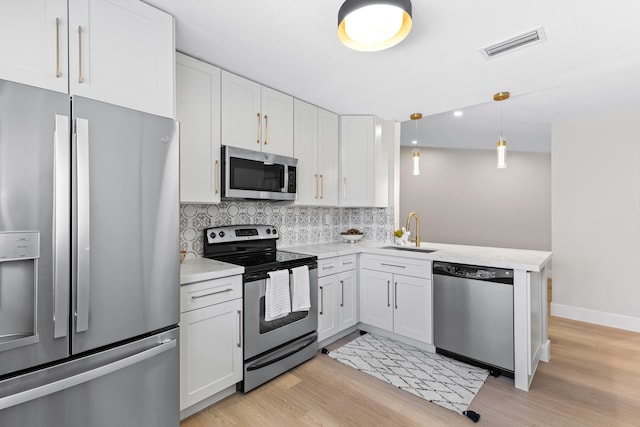 kitchen with pendant lighting, sink, stainless steel appliances, and white cabinets