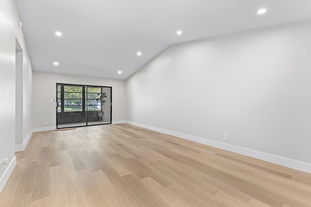 unfurnished room with vaulted ceiling and light wood-type flooring