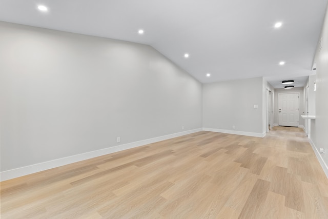 spare room featuring vaulted ceiling and light hardwood / wood-style flooring