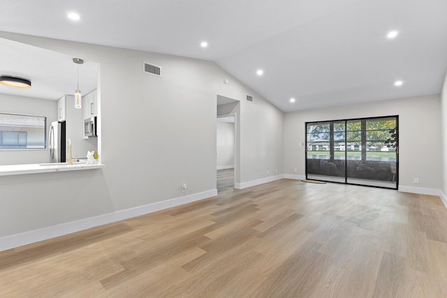 unfurnished living room featuring lofted ceiling and light hardwood / wood-style flooring