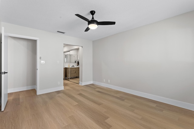 unfurnished bedroom featuring ensuite bath, ceiling fan, and light wood-type flooring